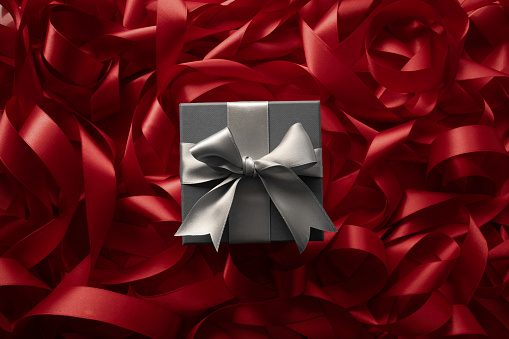 Gray gift box on red ribbon background.