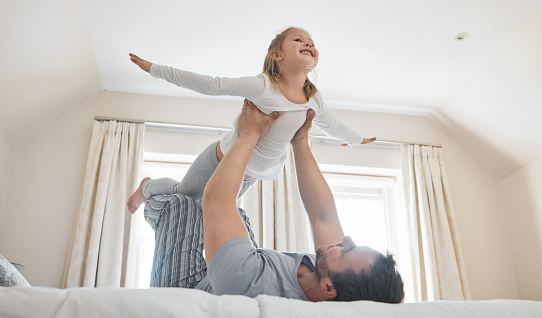 Child, dad and happy on bed for airplane games, support and relax for crazy fun in house. Father, girl kid and excited to fly in bedroom for freedom, fantasy and balance for play, trust and energy