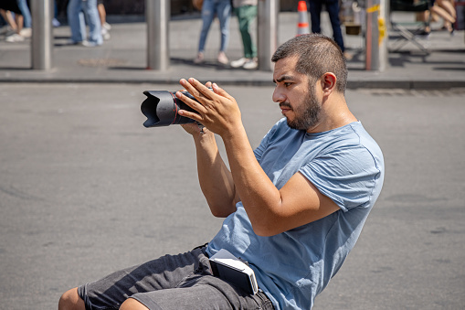 Times Square, Manhattan, New York, USA - August 12th 2023:  Man sitting in the street taking photographs with a professional digital camera