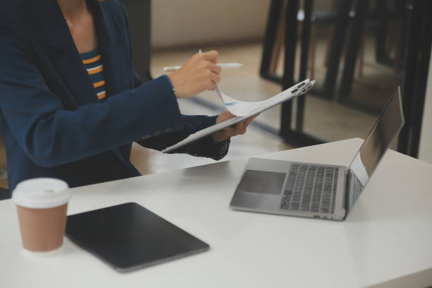 istock Asian Businesswoman Using laptop computer and working at office with calculator document on desk, doing planning analyzing the financial report, business plan investment, finance analysis concept. 1702540408