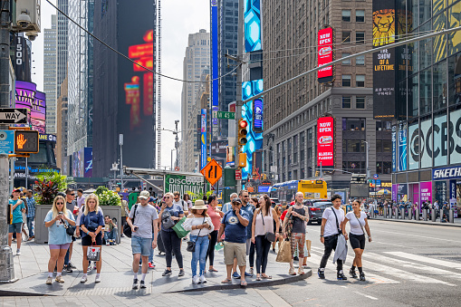 Times Square, Manhattan, New York, USA - August 12th 2023:  Large group of people waiting to cross the street in a zebra crossing