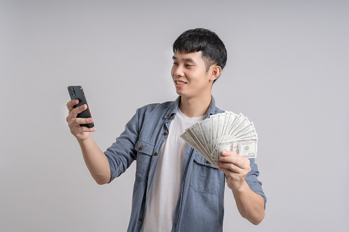 Man using smartphone and holding dollar cash banknotes.