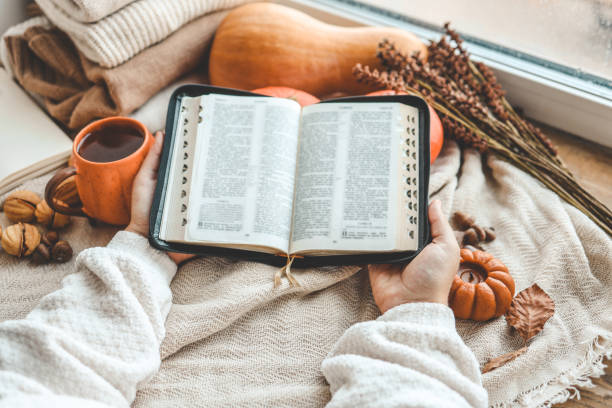 istock Open Bible in female hands in autumn interior 1702552814