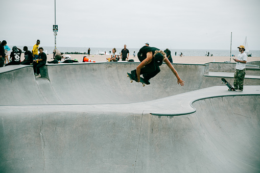 Venice Beach, CA, USA - Sep 17, 2023: The skater performs a transfer on a skateboard in the bowl at the skatepark on Venice Beach.