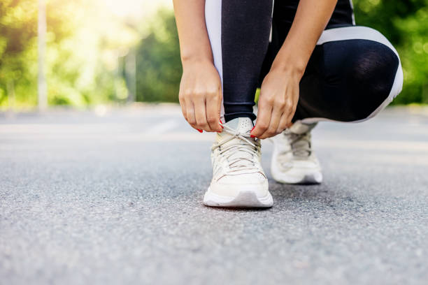 istock woman getting ready for jogging outdoors while lacing her sneakers 1702570641