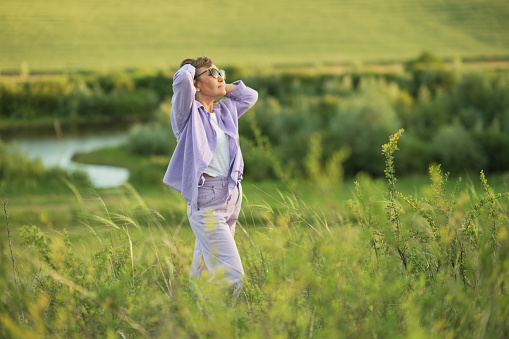 Picture of a fashion-forward senior woman expressing her style while enjoying the peace of a meadow.