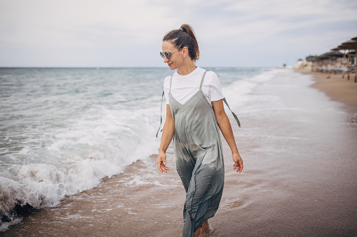 Woman walking on the beach by the sea, she is on vacation.
