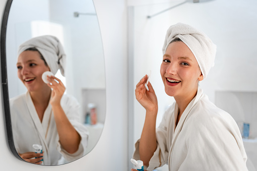 Young Woman cleaning face with cosmetic product