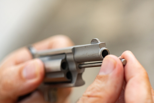 This is a photograph of an unrecognizeable man putting a small .22 caliber revolver pistol gun together at home in Florida, USA.