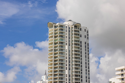 Beautiful view of high building on shores of Atlantic Ocean in Miami Beach on background of blue sky with white clouds. USA.
