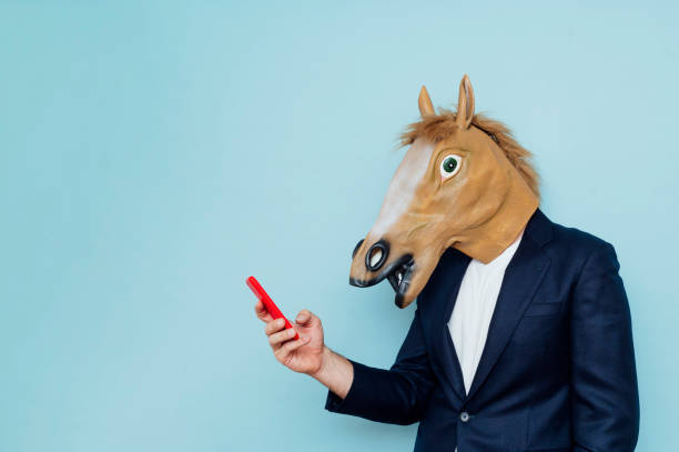 istock Businessman with horse mask using smartphone 1702698957