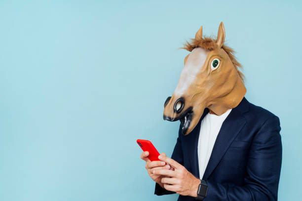 istock Businessman with horse mask using smartphone 1702698962