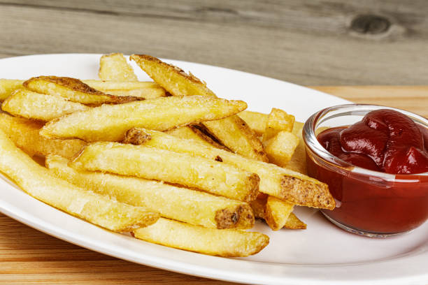 A plate of delicious Skin On French Fries A plate of delicious Skin On French Fries on a wooden background with Ketchup and copy space fried potato stock pictures, royalty-free photos & images