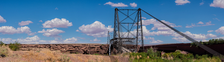 The Cameron Suspension Bridge is a significant piece of Arizona's transportation history and has played a crucial role in connecting the northern and southern parts of the state.  It was built in 1911 by the Midland Bridge Company of Kansas City, Missouri to provide a crossing over the Little Colorado River for both vehicles and pedestrians.  At the time of its construction, the Cameron Suspension Bridge was a modern engineering marvel and provided a reliable river crossing for travelers, particularly those heading to the Grand Canyon. It was crucial for the development of the region and facilitated trade and tourism in the area.  The Cameron Suspension Bridge is located near the Cameron Trading Post in Cameron, Arizona, USA.