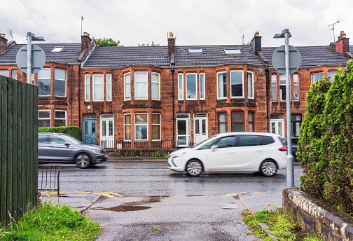 a row of traditional english old working class terraced houses on a street with grey cloudy sky