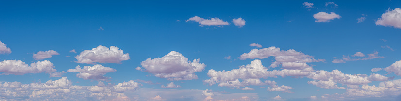 Cumulus clouds appear in a blue sky over the desert west of Kayenta, Arizona, USA.
