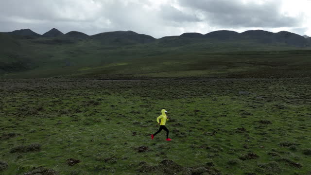 Aerial footage of woman trail runner cross country running on high altitude mountain top, slow motion