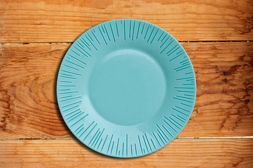 Empty ceramic blue plate isolated on wood background