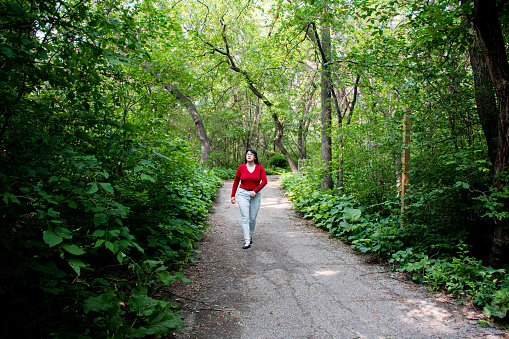A confident and curvy 40-year-old woman gracefully walks along a serene forest path, finding solace and connection with the natural world.