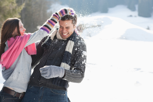 Couple throwing snow and enjoying winter time in park, full of snow. Couple throwing snow and enjoying winter.