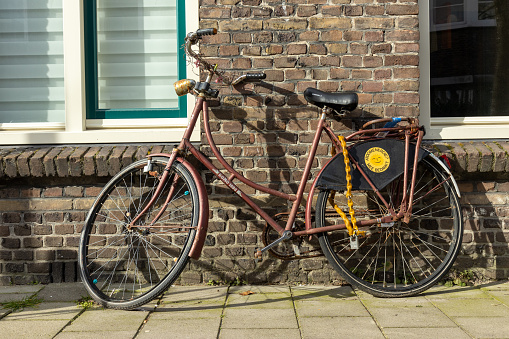 Rusty old bike parked against a house in Utrecht in the Netherlands. 11 march 2023.