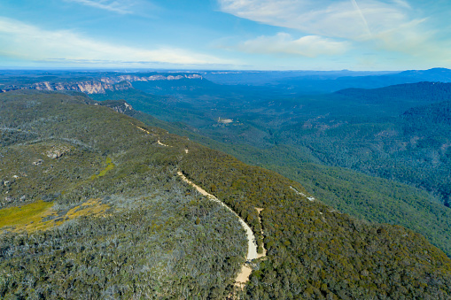 Drone aerial photograph of Kedumba Valley Road winding along the cliff top through the forest of gum trees in the Blue Mountains in New South Wales in Australia