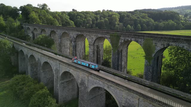 Narrowboat crossing canal over Chirk Aqueduct, Railway Viaduct in background - stationary aerial drone - Welsh, English border, Sept 23