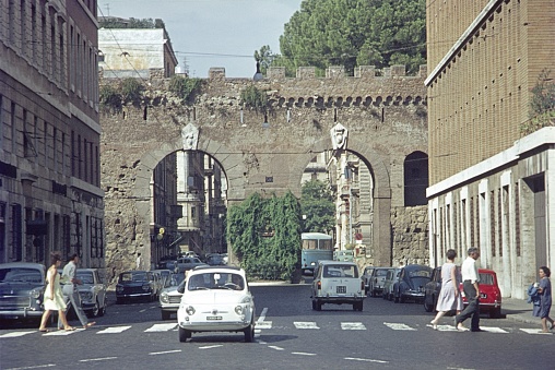 Rome, Lazio, Italy, 1965. Street scene with traffic and pedestrians in Rome. In the background the old city wall.