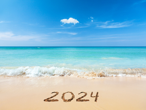Year 2024 hand written on sandy beach