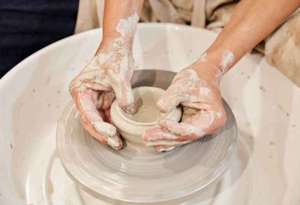 istock Unrecognizable potter creating clay pot on wheel in workshop 1702847164