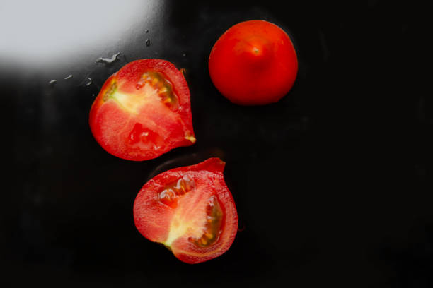istock red tomato, whole and in halves on a black background, ripe tomatoes 1702860768