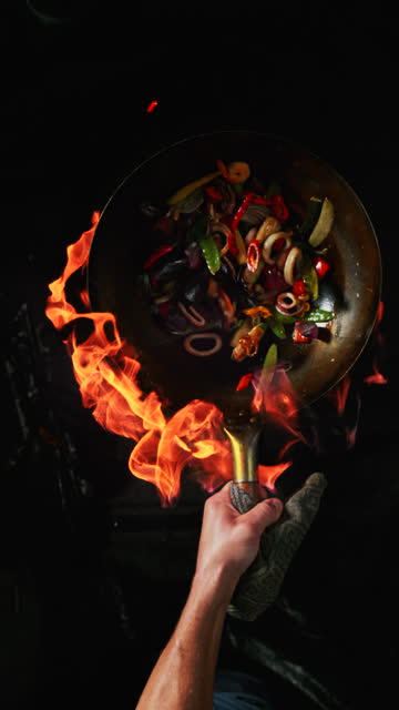 Skilled cook flipping vegetables in a wok