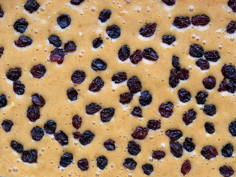Macro photography of a  raw cake mix with raisins on top, ready to go into de oven.
