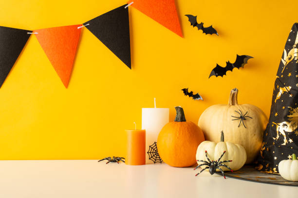 istock Craft a bewitching Halloween table setting. Side view shot of a tabletop decorated with themed elements, pumpkins, bats, spiders, candles, a mystical hat, and festive flag garland on a yellow wall 1702909118