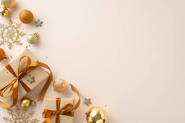 istock Festive holiday presents display with gift boxes, elegant ribbon bows, ornate tree ornaments, golden baubles, stars, snowflake decor, confetti on pastel backdrop for your message. Top view layout 1702909132