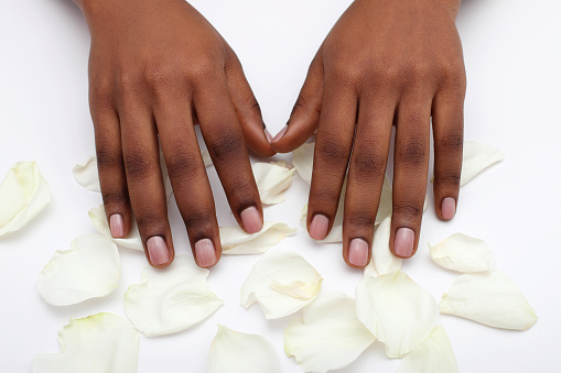 Nude beige manicure nails of black afro girl and rose petals