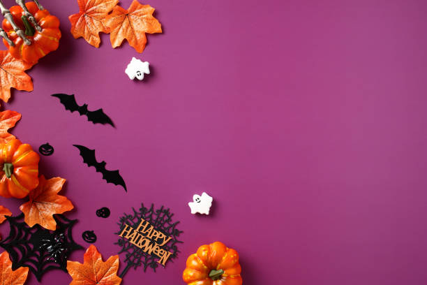istock Halloween flat lay composition with maple leaves, pumpkins, bats, ghosts, spiders webs on violet background. 1702921978