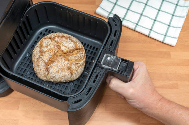 HAND BAKING RUSTIC SOURDOUGH BREAD IN AIR FRYER AT THE KITCHEN. TOP VIEW.