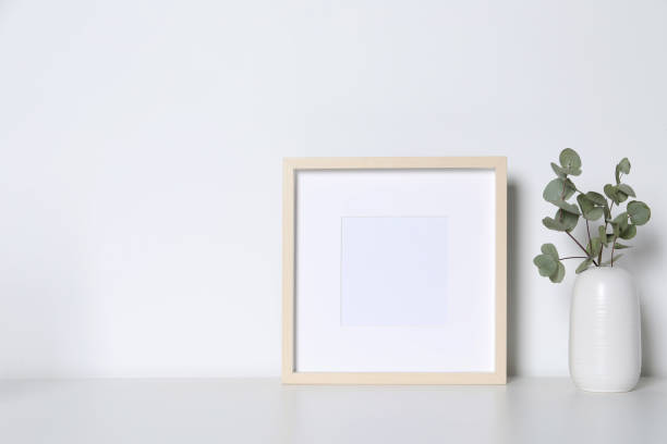 istock Empty photo frame and vase with decorative eucalyptus leaves on white table. Mockup for design 1703045775