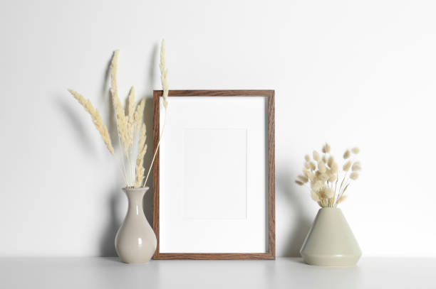 istock Empty photo frame and vases with dry decorative spikes on white table. Mockup for design 1703046309