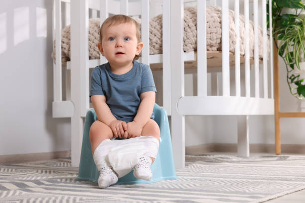 istock Little child sitting on plastic baby potty indoors. Space for text 1703055597