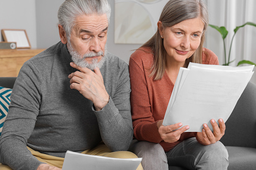Elderly couple with papers discussing pension plan in room