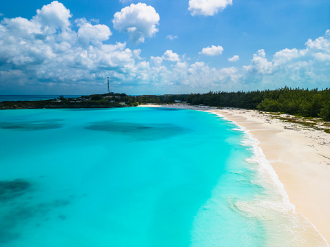 Small beautiful paradise island for tourists with palms, beach, big stones and beach plank beds for sunbathing. Caribbean travel destination dream. Unrecognizable people on island