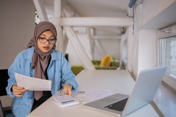 istock Young woman using calculator while going through bills and home finances 1703117348