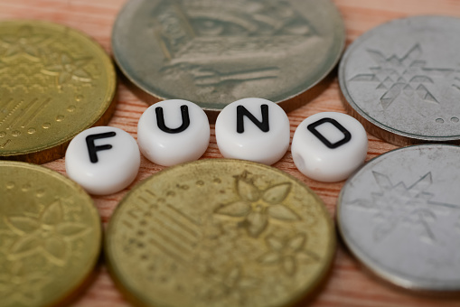 Coins and alphabet beads with text FUND.a fund refers to a pool of money or capital that is collected from multiple investors or contributors for a specific purpose