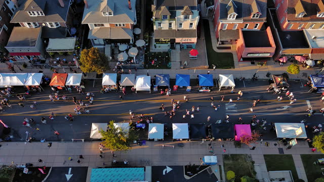 Fall season – time for Street Food Festival. Food trucks and cafes during Autumn Street Festival on crowded avenue. Aerial footage with panning along street camera motion