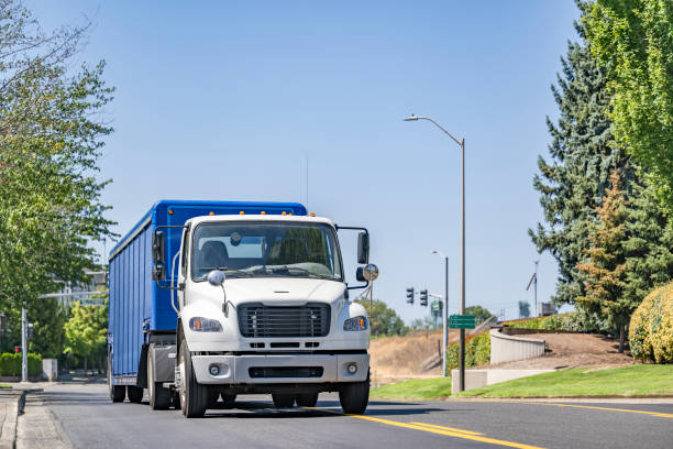 istock Day cab white big rig semi truck transporting beverages in low profile special semi trailer driving on the city road making local delivery 1703205814