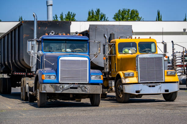 istock Old style day cab big rig semi trucks with dump trailers standing in row on the marked spots warehouse parking lot 1703215099