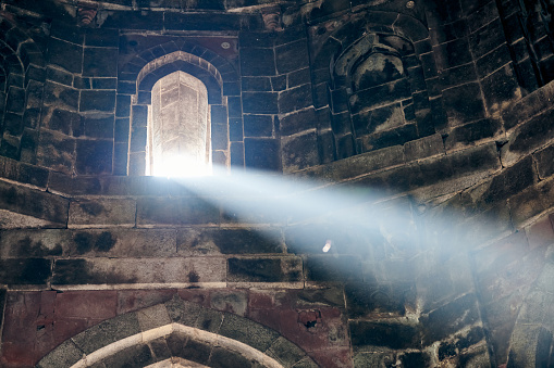 Beam of light from window of ancient indian tomb Bada Gumbad in New Delhi, India, beautiful white ray of light in old tomb interior, mystical and mysterious atmosphere of ancient monument in India