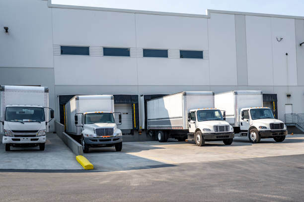 istock Different makes and models of the middle duty day cab semi trucks with box trailers loading commercial cargo standing in warehouse docks 1703218103